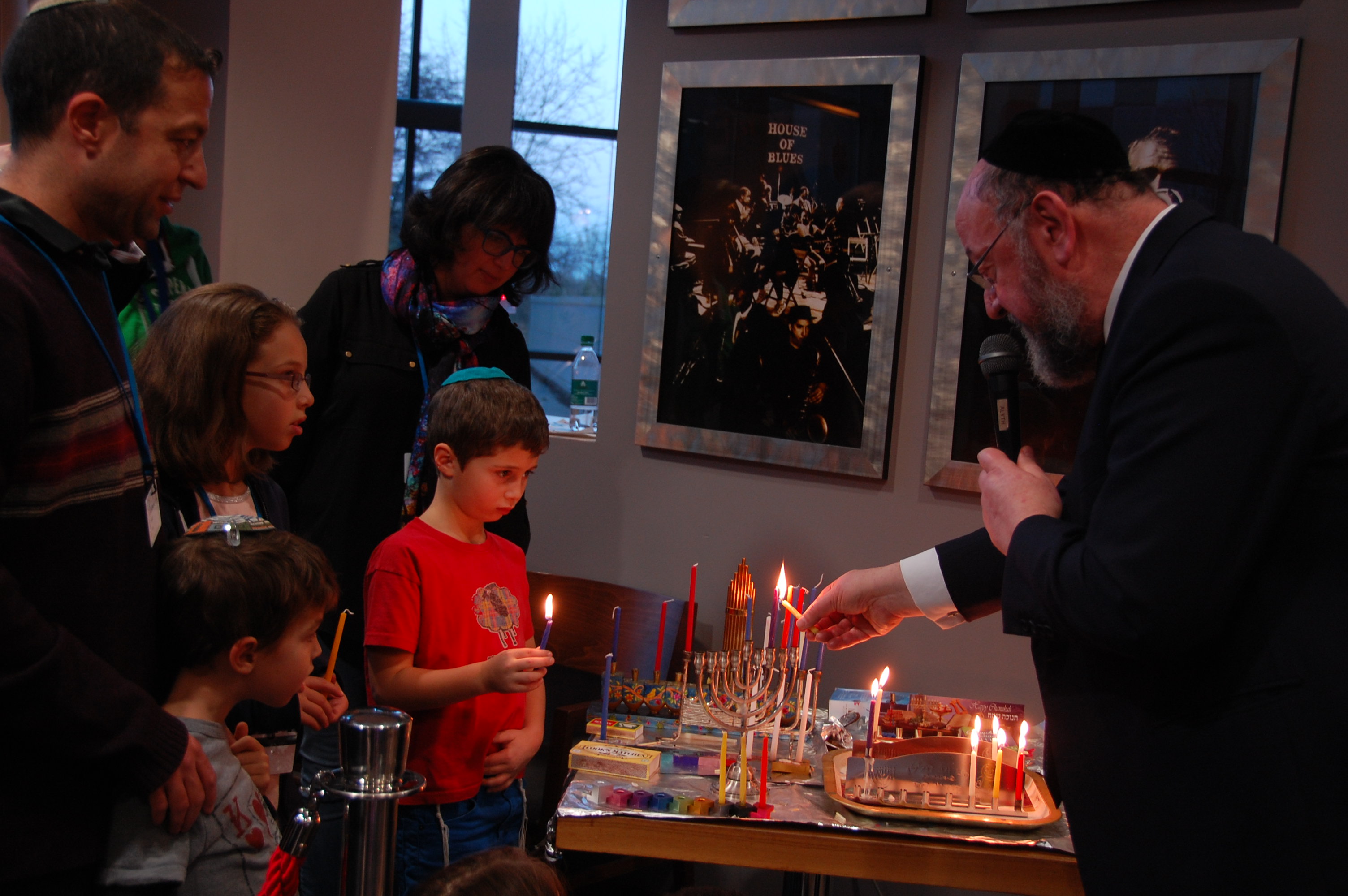 Rabbi Ephraim Mirvis, the chief rabbi of the United Hebrew Congregations of the Commonwealth, lights Hanukkah candles with children attending Limmud Conference '16, Dec. 26, 2016. (Ranana Dine)