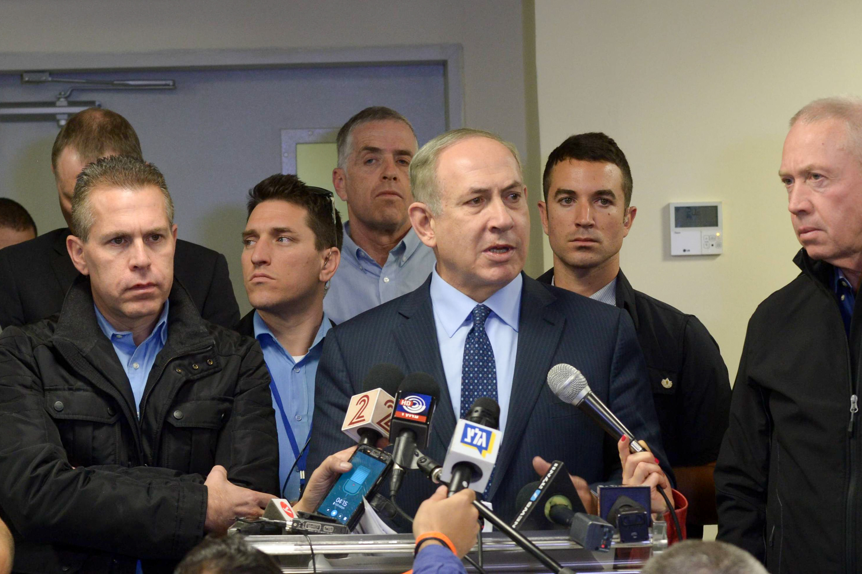 Prime Minister Benjamin Netanyahu, at microphone, surrounded by security and government officials, speaks at a briefing in Haifa about the fires raging in the northern city and elsewhere in Israel, Nov. 24, 2016. (Amos Ben Gershom/Israeli Government Press Office)