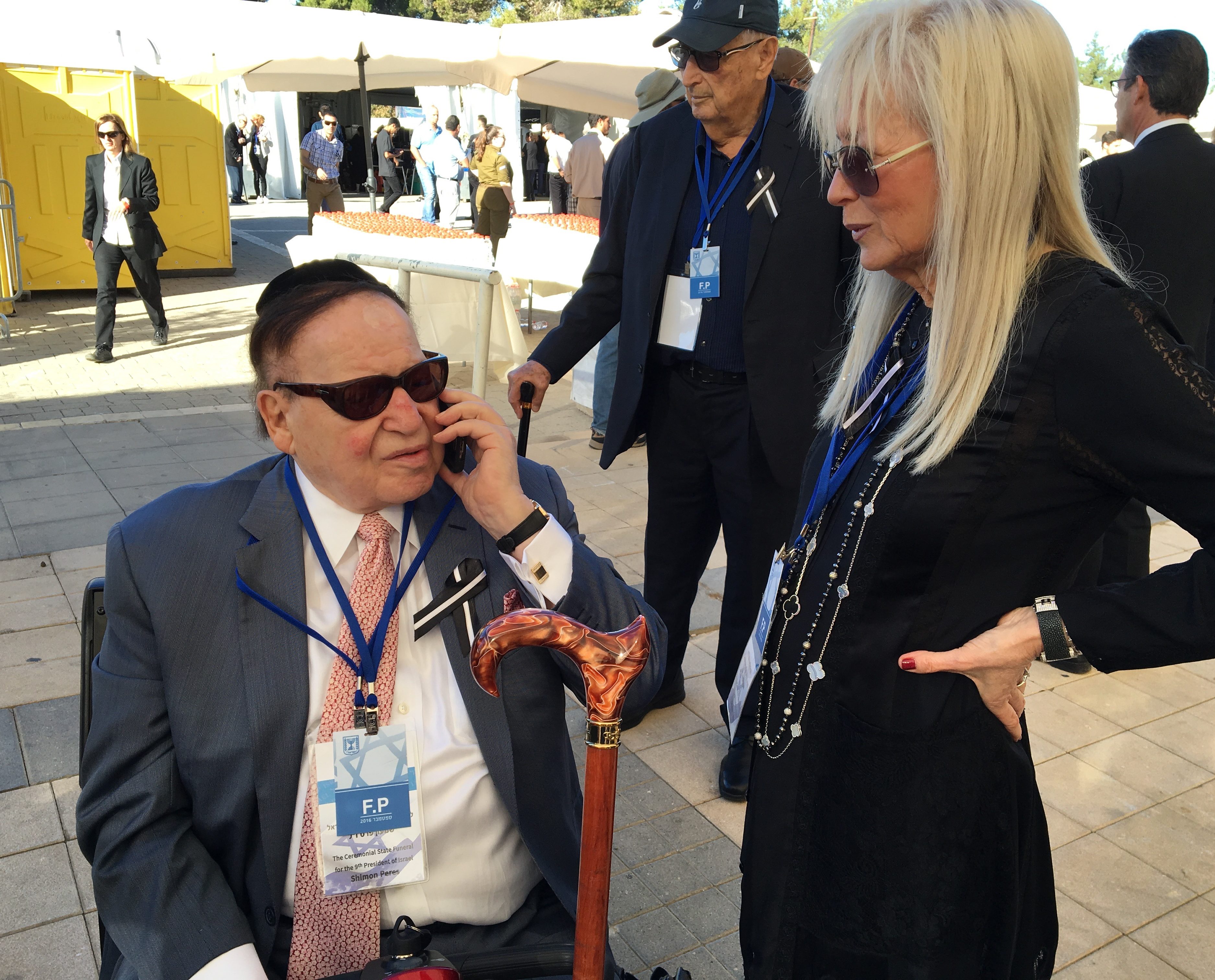Sheldon Adelson, with wife Miriam, speaking with Army Radio by phone at the funeral of Shimon Peres at Mount Herzl national cemetery in Jerusalem, Sept. 30, 2016. (Andrew Tobin)