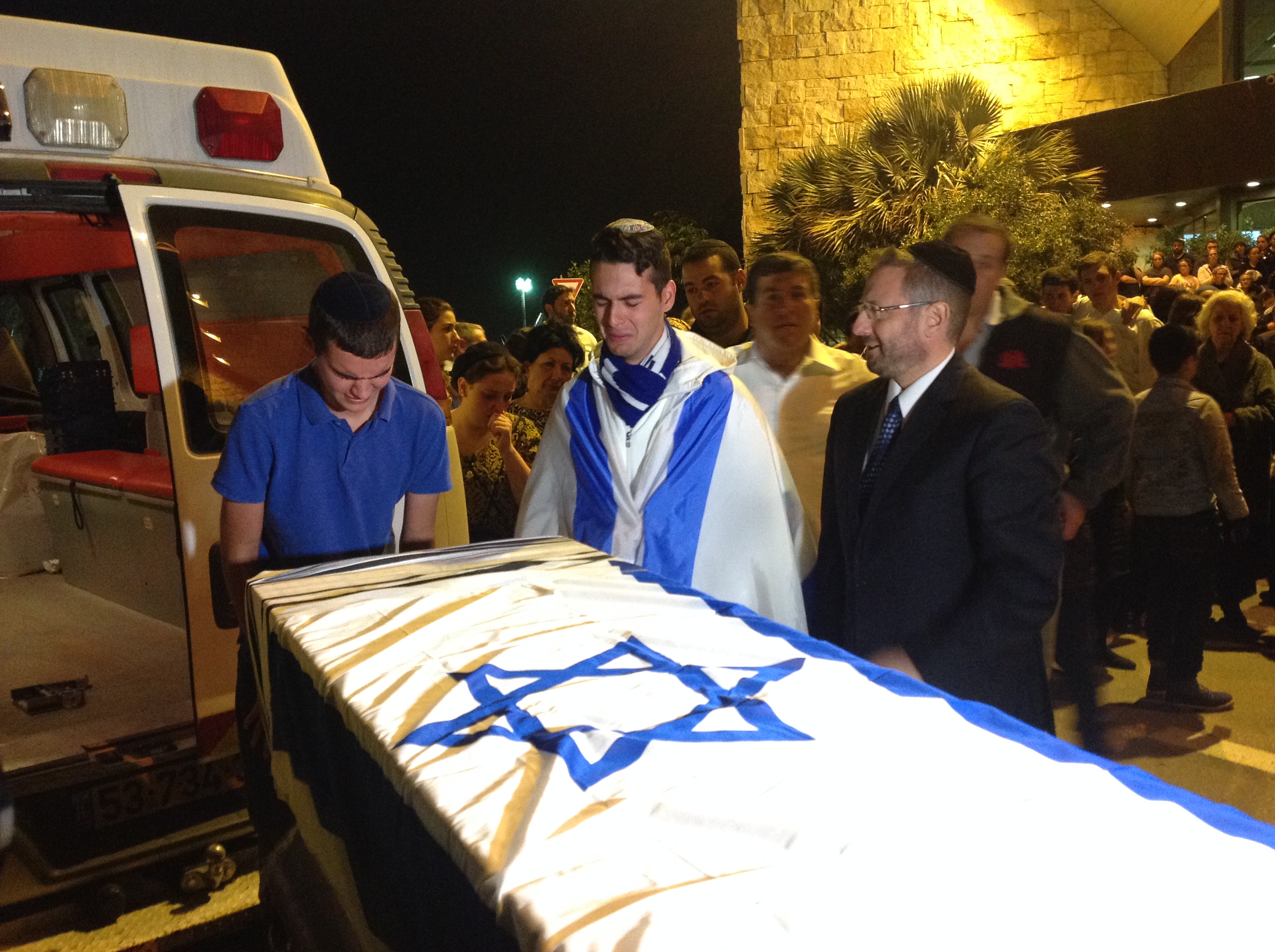Friends of Ezra Schwartz grieving over the coffin of the American terror victim at a service at Ben Gurion Airport in Israel before the body was repatriated to Boston for his funeral the following day, Nov. 21, 2015. (Ben Sales)