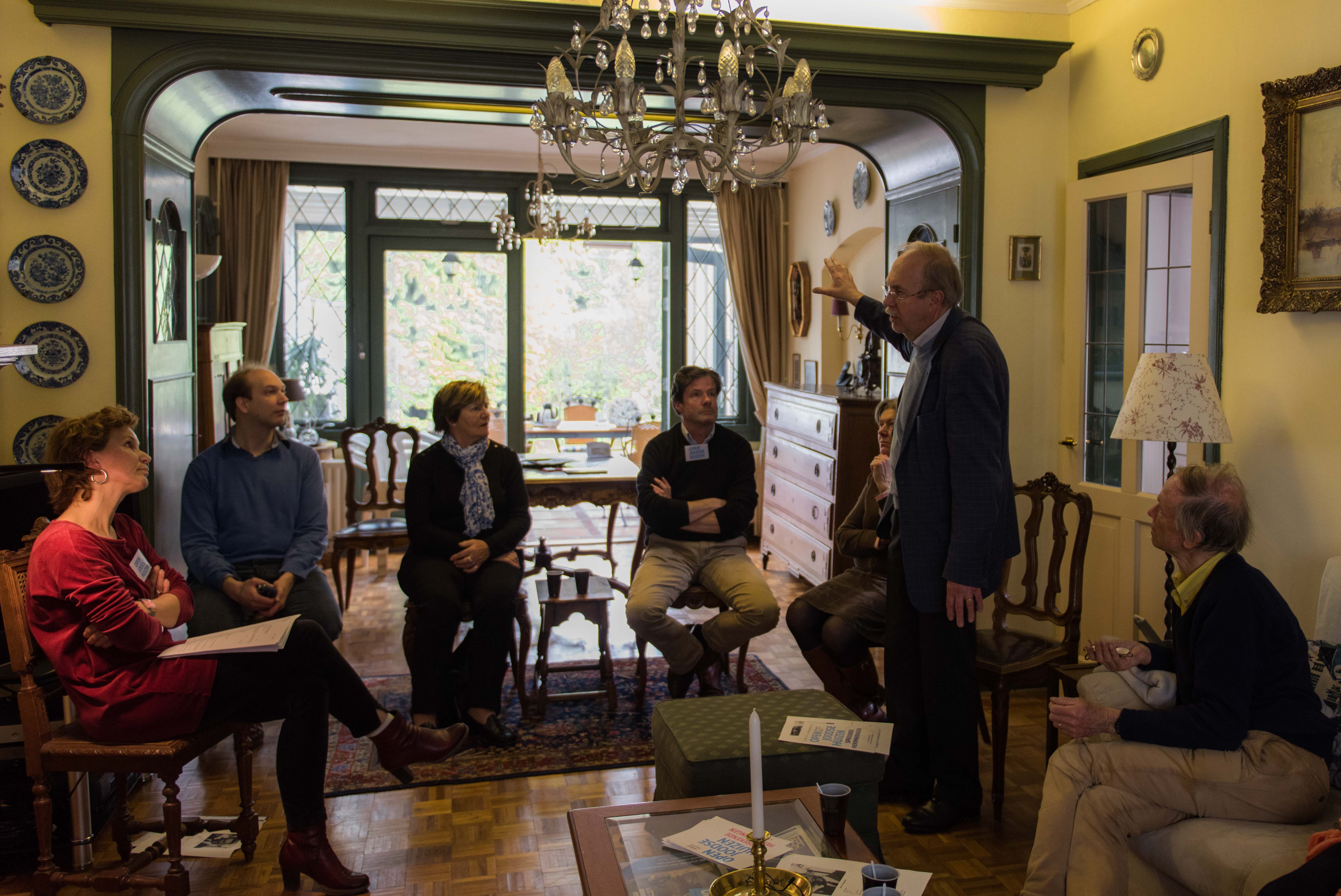 Kees van den Heuvel, standing, talking to guests about the Jewish family that once lived in what is now his home in the Netherlands town of Vught, April 30, 2016. (Cnaan Liphshiz)