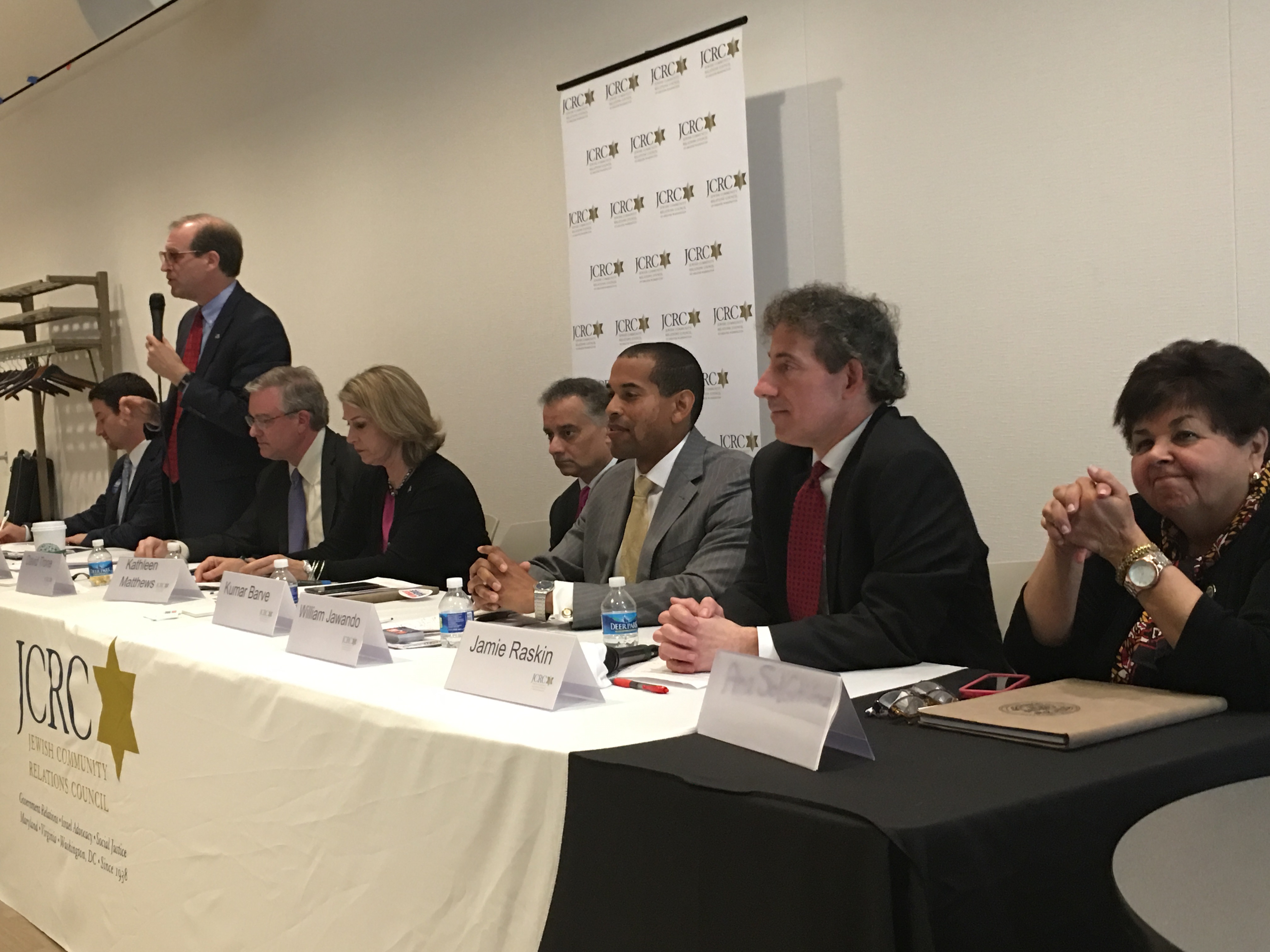 Left to right: Congressional candidates Joel Rubin, David Anderson (standing), David Trone, Kathleen Matthews, Kumar Barve, Will Jawondo, Jamie Raskin and Ana Sol Gutierrez debating in Rockville, Md., at an event convened by the Jewish Community Relations Council of Greater Washington, April 17, 2016. (Ron Kampeas)