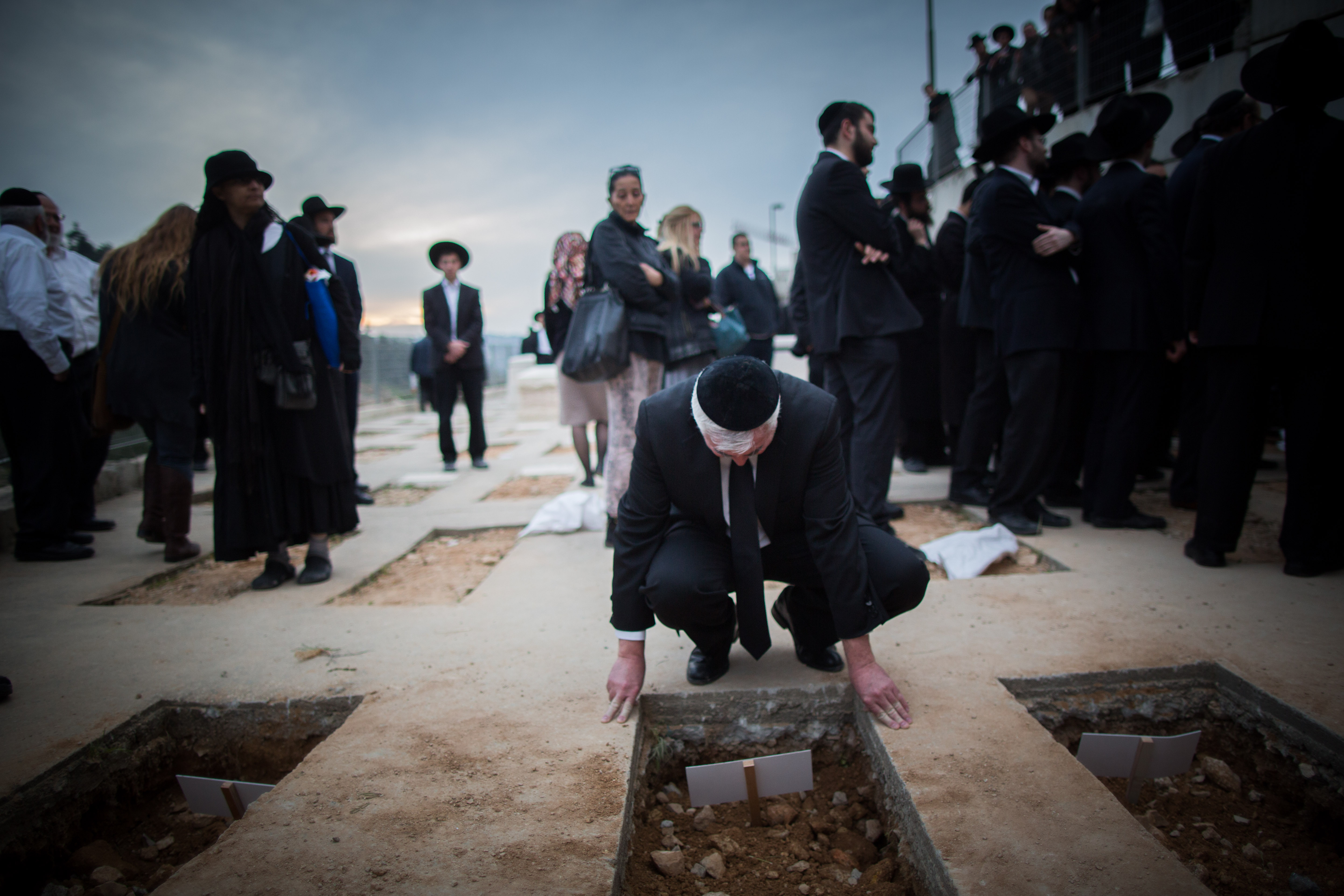 A mourner near the fresh graves of the seven children from the Sassoon family during their funeral in Jerusalem, March 23, 2015. (Yonatan Sindel/Flash90)