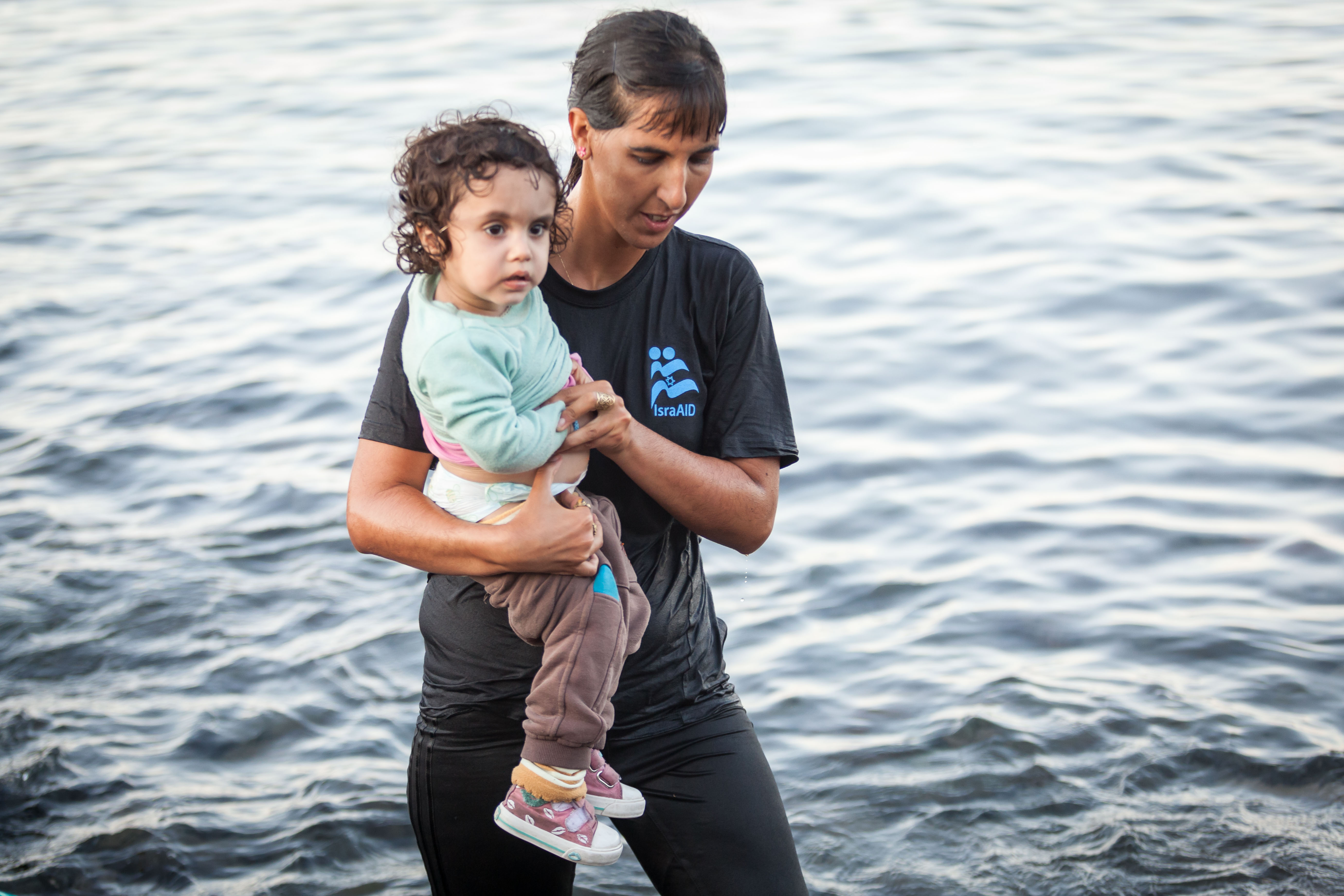 Tali Shaltiel, an Israeli physician, taking a Syrian child from a dinghy that arrived at a beach on the Greek island of Lesbos. (Boaz Arad/IsraAid)