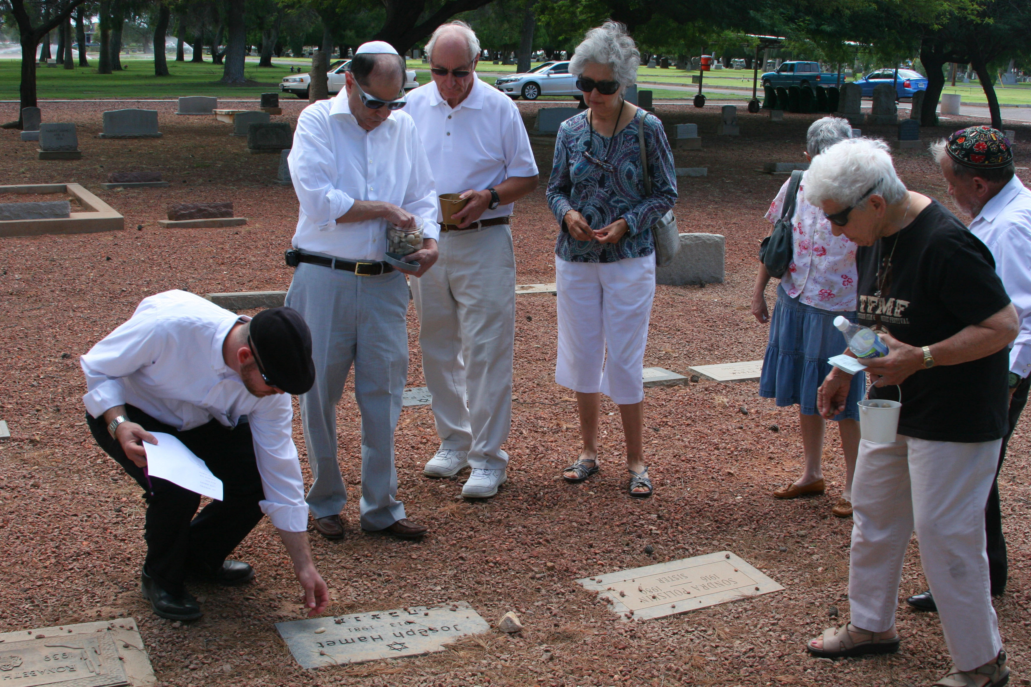 (L-R) Cantor Avraham Alpert, Alan Ziblat, Ron Cohen, Mary Bell, Barbara Snyder, Honey Manson and Jerry Snyder place memorial stones on graves at Evergreen Cemetery.