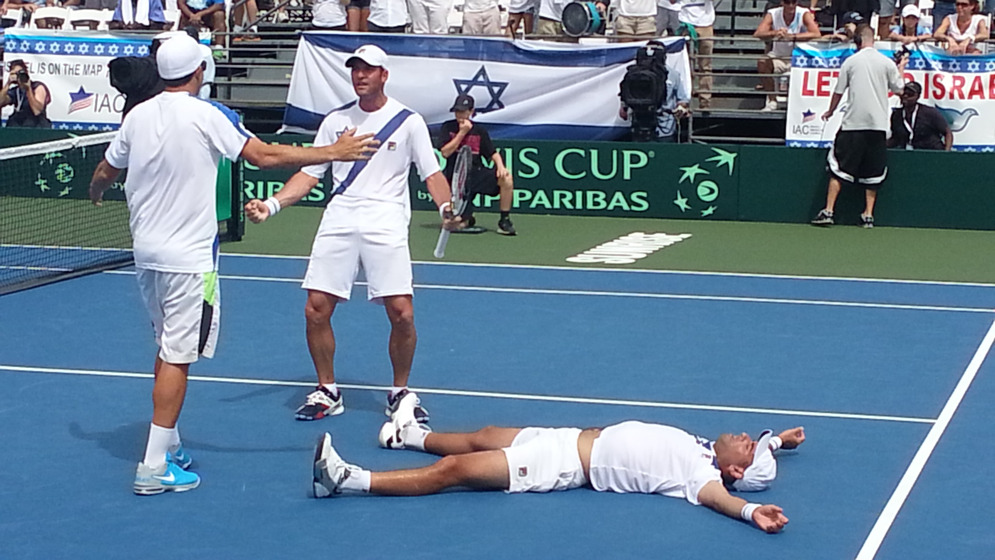 Israel's Andy Ram sprawled on the court following his five-set doubles victory with partner Yoni Erlich, holding racket, against Argentina in a Davis Cup match in Sunrise, Fla., Sept. 13, 2014. (Andrea Eidman)