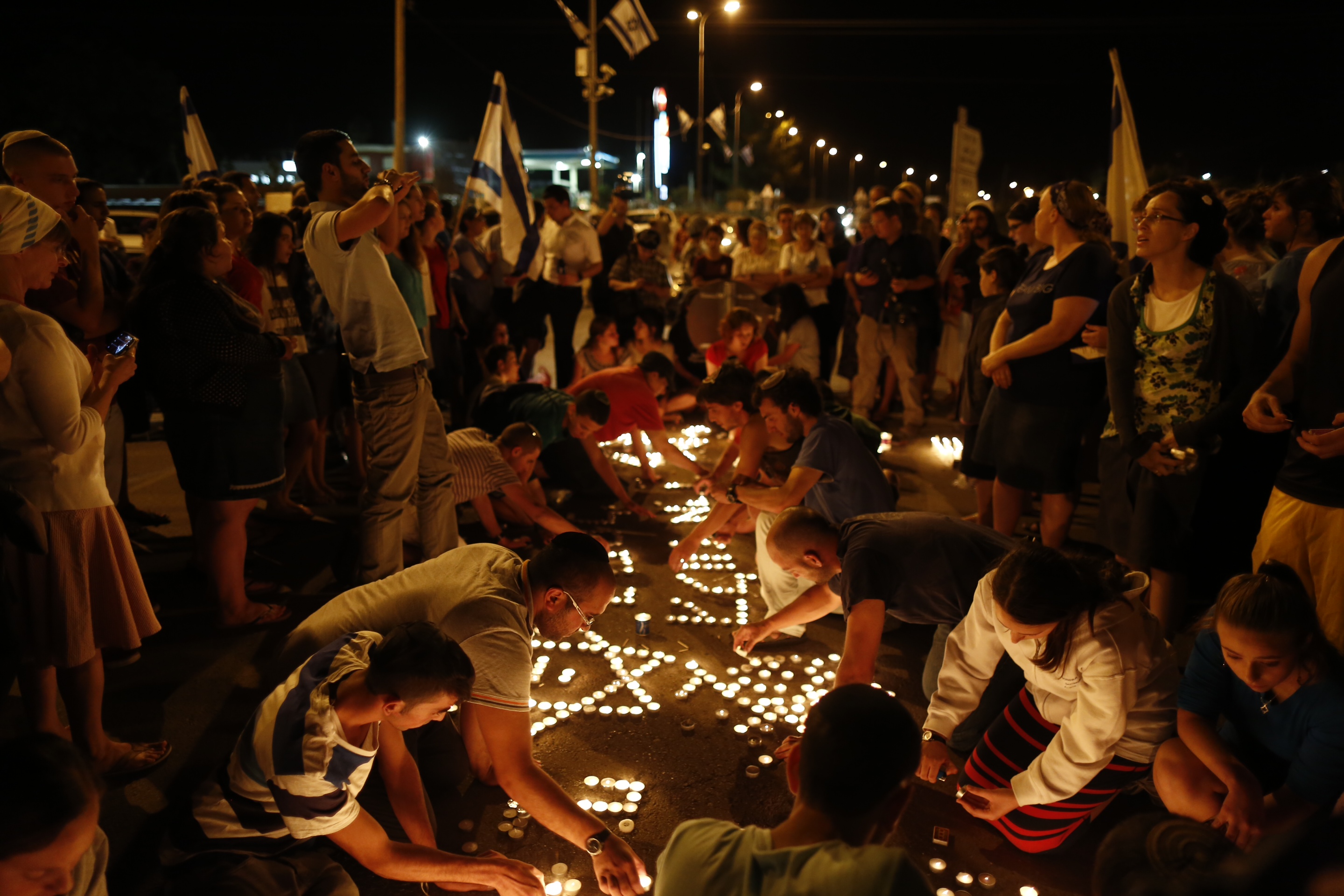 At the hitchhiking spot in the West Bank where teenagers Eyal Yifrach, Naftali Fraenkel and Gilad Shaar were abducted, Israelis light memorial candles after the discovery of their bodies, June 30, 2014. (Yonatan Sindel/Flash 90)