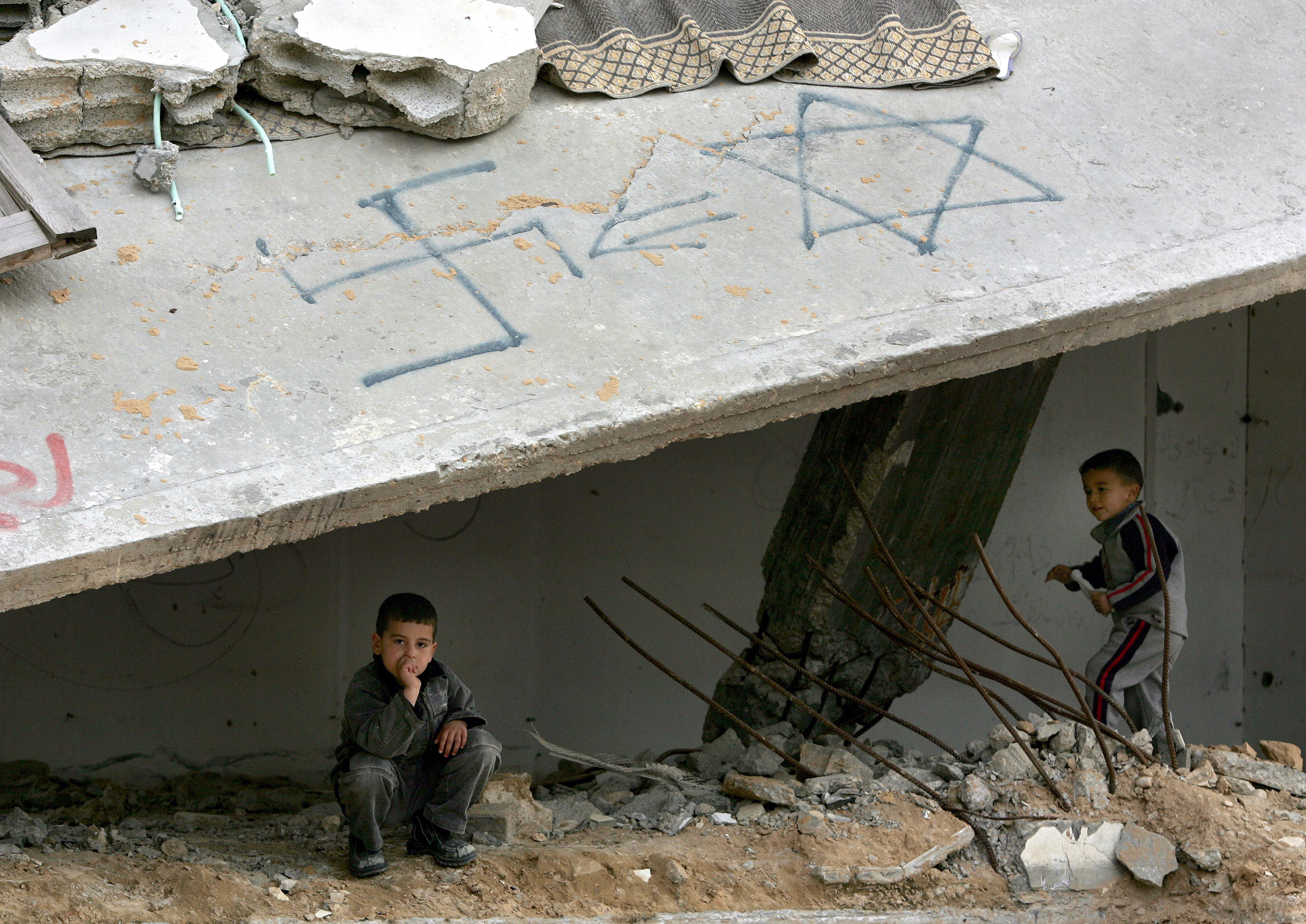 Palestinian children play in a damaged building with a swastika and the Star of David painted on it in a Gaza refugee camp in 2005. The ADL survey found that 93 percent of respondents in the West Bank and Gaza have anti-Semitic views. (Abid Katib/Getty Images)
