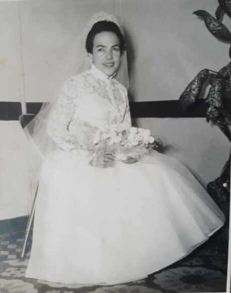 A woman seated wearing a wedding dresss and veil.